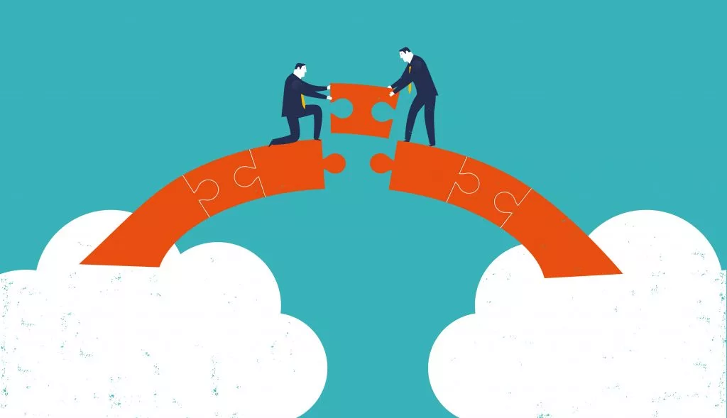 Two businesspeople connecting puzzle pieces on a bridge, symbolizing collaboration.